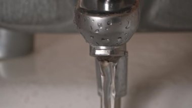 Banyodaki musluktan akan suyun yakın çekimi. Musluktan gelen su akışı. Şehir borularında suyun saflığı.