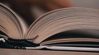 Beyaz kitaptaki sayfaları yavaş çekimde kapatıyoruz. Kitap okumak, istihbarat. Sayfalar peş peşe akıyor. Kadınların elleri kitap sayfalarını karıştırır..