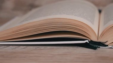 Beyaz kitaptaki sayfaları yavaş çekimde kapatıyoruz. Kitap okumak, istihbarat. Sayfalar peş peşe akıyor. Kadınların elleri kitap sayfalarını karıştırır..