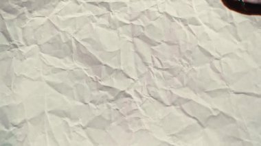 White paper burns from above on a green background copy space. The sheet of paper burns and reveals a green background for pasting.
