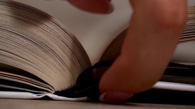Beyaz kitaptaki sayfaları yavaş çekimde kapatıyoruz. Kitap okumak, istihbarat. Sayfalar peş peşe akıyor. Kadınların elleri kitap sayfalarını karıştırır..