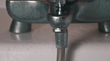 Banyodaki musluktan akan suyun yakın çekimi. Musluktan gelen su akışı. Şehir borularında suyun saflığı.