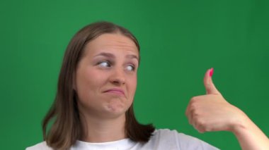 Keyifli güzel bir kız yeşil bir arka plana benzer bir şey koyar. Genç kadın çok mutlu, yeşil ekranda izole edilmiş, krom ada.