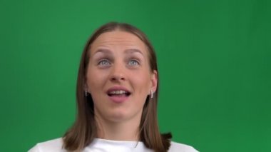 Mutluluktaki güzel kız ellerini yeşil bir arka planda tutarak yüzünü kapatıyor. Genç kadın çok mutlu, yeşil ekranda izole edilmiş, krom ada. Kadın başarı için gülümsüyor ve çığlık atıyor..