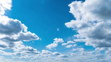 White fluffy clouds slowly float through the blue daytime sky timelapse. Beautiful skies are moving. Airy snow-white clouds move to the side.