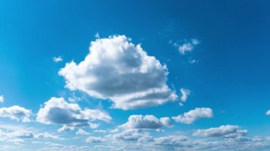 Beyaz kabarık bulutlar mavi gündüz vakti gökyüzünde yavaşça süzülür. Güzel gökyüzü hareket ediyor. Kar beyazı bulutlar yana doğru hareket ediyor..