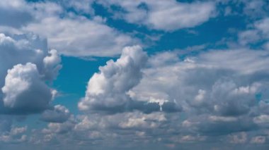 Beyaz kabarık bulutlar mavi gündüz vakti gökyüzünde yavaşça süzülür. Güzel gökyüzü hareket ediyor. Kar beyazı bulutlar yana doğru hareket ediyor..