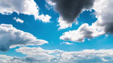 White fluffy clouds slowly float through the blue daytime sky timelapse. Beautiful skies are moving. Airy snow-white clouds move to the side.