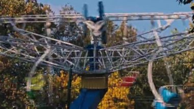 Çok renkli çocuklar sonbahar parkında papatya çayı sallıyor. Çocuklar için eğlence parkı. Halk parkındaki atlıkarıncalarda çocuklar eğleniyor..