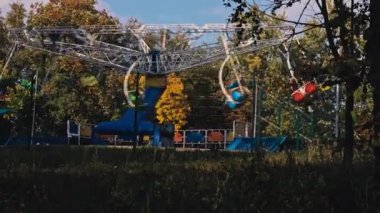 Çok renkli çocuklar sonbahar parkında papatya çayı sallıyor. Çocuklar için eğlence parkı. Halk parkındaki atlıkarıncalarda çocuklar eğleniyor..