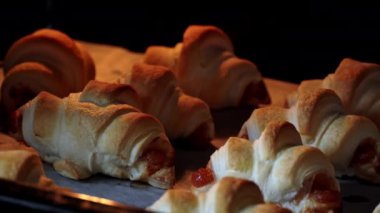 Doldurulmuş kruvasanlar fırında pişiyor. Fırından çıkan pastaların ışıkla yakın çekimi. Ev yapımı lezzetli hamur işleri. Puf böreği ve tatlı dolgulu çörekler..