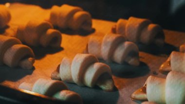 Doldurulmuş kruvasanlar hızlandırılmış fırında pişirilir. Fırından çıkan pastaların ışıkla yakın çekimi. Ev yapımı lezzetli hamur işleri. Puf böreği ve tatlı dolgulu çörekler..