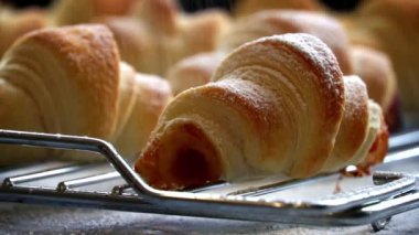 Ağır çekimde pudra şekeri serpiştirilmiş pofuduk kruvasanlar. Yakın plan hamur işleri pudra şekerle süslenir. Ev yapımı lezzetli hamur işleri. Puf böreği ve tatlı dolgulu çörekler..