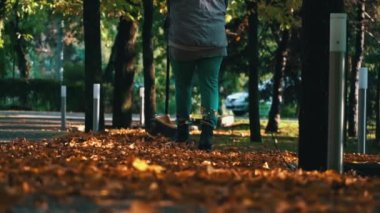Aşağıdan kumsaldaki parkta sonbahar sarı yapraklarını temizliyorum. Temizlikçi portakal yapraklarını kavrayıp, onları büyük bir yığına süpürüyor. Bölgenin sonbahar temizliği.
