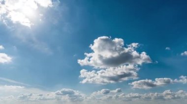 Beyaz kabarık bulutlar mavi gündüz vakti gökyüzünde yavaşça süzülür. Güzel gökyüzü hareket ediyor. Kar beyazı bulutlar yana doğru hareket ediyor..
