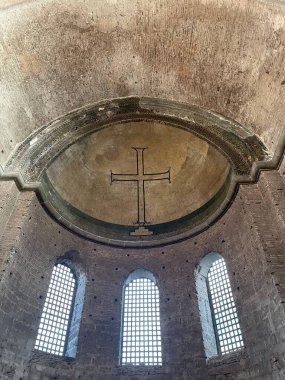 Büyük pencereleri ve haçı olan eski kilise binası. 