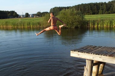 Letonya, Riga bölgesi, 17.08.2021. Çocuk suya atlıyor..