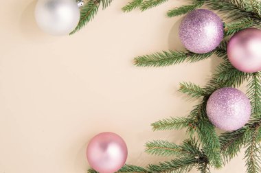 Parlak parıltılı süslemeleri ve şampanya rengi arka planında Noel ağacı yeşil dalları olan bir tatil düzenlemesi. En az yeni yıl görüntüsü. Düz yatıyordu.