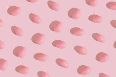 Pembe Paskalya yumurtalarından yapılmış yaratıcı bir model. Minimum düz estetik uzanıyordu. Güneşli gün gölgesiyle bahar ve tatil görüntüsü.