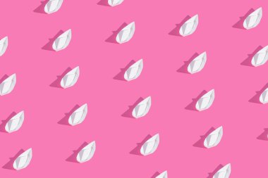 Kalın pembe arka planda kağıt teknelerden yapılmış yaratıcı desen. Minimum yaz konsepti. Düz bir estetik..