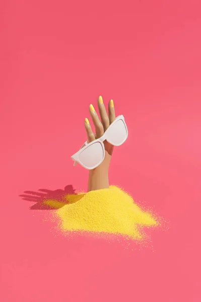 Mão Feminina Plástico Saindo Areia Segurando Óculos Sol Fundo Rosa — Fotografia de Stock