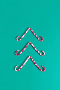 Yeşil arka planda şeker kamışlarından yapılmış Noel ağacı şekilli tatil konsepti. En az yeni yıl görüntüsü. Kopyalama alanı olan düz.