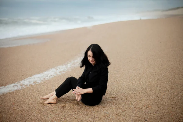 Bulutlu bir havada, okyanus kıyısındaki sahilde güzel bir kız. Marimar Plajı, Portekiz