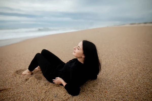 Bulutlu bir havada, okyanus kıyısındaki sahilde güzel bir kız. Marimar Plajı, Portekiz