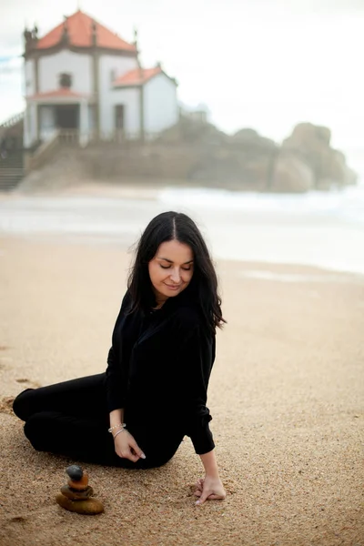 Portekiz 'de Marimar plajında genç ve güzel bir kız kumsalda oturuyor. Arkasında Ortodoks Kilisesi var..