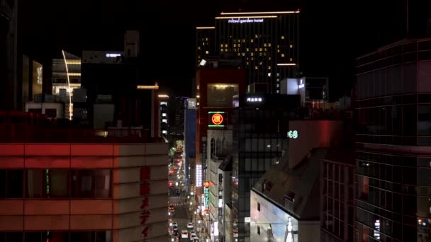 Tokijská ulice v noci s osvětlenou neonovou značkou a výškovými budovami. — Stock video