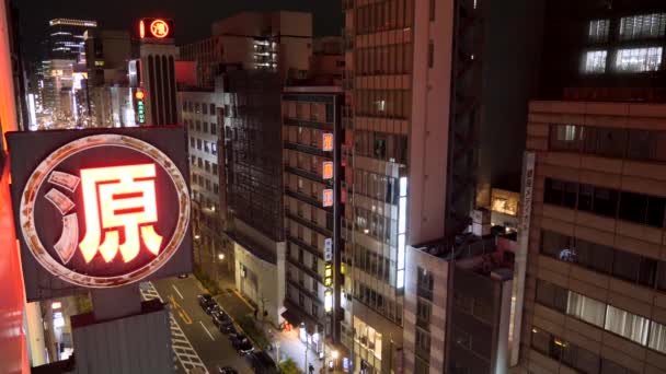Tokijská ulice v noci s osvětlenou neonovou značkou a výškovými budovami. — Stock video