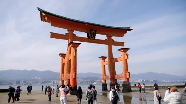 Gente caminando frente al gran Torii de Miyajima. Torii flotante . — Vídeos de Stock