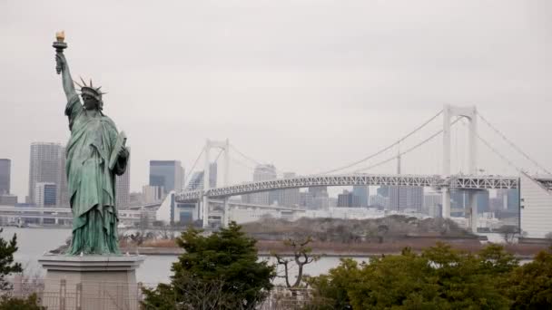 Odaiba Socha svobody a Tokijské mrakodrapy s duhovým mostem v pozadí, Japonsko. — Stock video