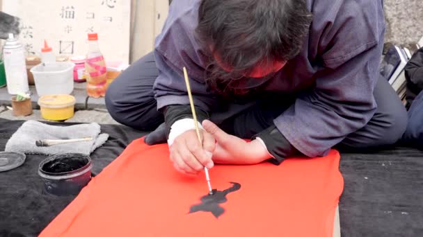 Japanese man painting black cat with a brush and black ink, Kyoto. Calligraphy. — Stock Video