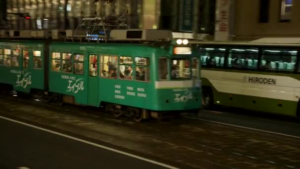 Forgalmas forgalom Hirosima szívében. Villamos, busz és éjszaka közlekedő autók. — Stock videók