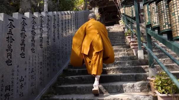 Rohanó buddhista szerzetes fel a lépcsőn a buddhista templomba imádkozni..