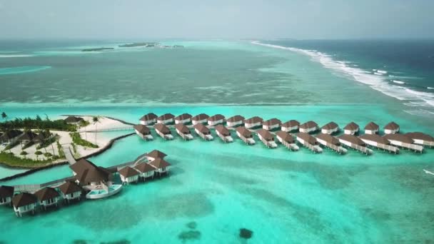 Drohnenvideo von einem exotischen türkisfarbenen Paradies mit Sandstrand und blauer Lagune auf den tropischen Malediven. Luftaufnahme der Wasser-Villa-Bungalows. Hochwertiges 4k Filmmaterial. Luxuriöses Resort auf den Malediven.