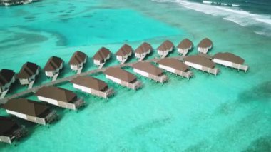 Tropik Maldivler 'de kumlu kumlu ve mavi lagünü olan egzotik turkuaz cenneti gösteren hava aracı videosu. Su villası bungalovlarının havadan görünüşü. Yüksek kalite 4K görüntü. Maldivler 'deki lüks tatil beldesi.