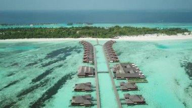 Tropik Maldivler 'de kumlu kumlu ve mavi lagünü olan egzotik turkuaz cenneti gösteren hava aracı videosu. Su villası bungalovlarının havadan görünüşü. Yüksek kalite 4K görüntü. Maldivler 'deki lüks tatil beldesi.