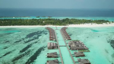 Tropik Maldivler 'de kumlu kumlu ve mavi lagünü olan egzotik turkuaz cenneti gösteren hava aracı videosu. Su villası bungalovlarının havadan görünüşü. Yüksek kalite 4K görüntü. Maldivler 'deki lüks tatil beldesi.