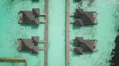 Tropik Maldivler 'de kumlu kumlu ve mavi lagünü olan egzotik turkuaz cenneti gösteren hava aracı videosu. Su villası bungalovlarının havadan görünüşü. Yüksek kalite 4K görüntü. Maldivler 'deki lüks tatil beldesi.
