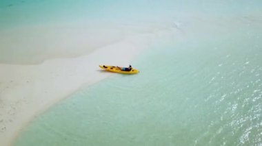 Sarı Kano 'nun Maldivler' de bir kum yığınına park ettiği hava aracı videosu. Maldivler 'de etkinlik ve Gevşeme. Turkuaz sakin denizle egzotik Maldivler 'de kayak yapmak. Cennette kayak yaparken. 