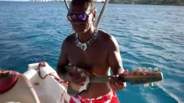 Bora Bora, Tahiti - July 23, 22: Local Tahitian playing the ukulele while we sail his small boat around Bora Bora, Tahiti, French Polynesia. Luxury travel vacation, honeymoon exotic destination