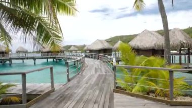 Man walking around water villas, Bora Bora, Tahiti, French Polynesia. Luxury travel vacation, romantic getaway, honeymoon exotic destination. 4K footage.