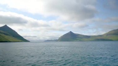 Ferry arriving to Kalsoy Island. Amazing Faroese nature. Faroese Cliffs and mountains. Green hills and beautiful rocky mountains. View to a Kalsoy Island. Sunny day in summer. 4k footage