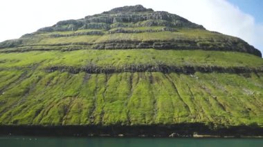 Ferry arriving to Kalsoy Island. Amazing Faroese nature. Faroese Cliffs and mountains. Green hills and beautiful rocky mountains. View to a Kalsoy Island. Sunny day in summer. 4k footage