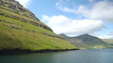Ferry arriving to Kalsoy Island. Amazing Faroese nature. Faroese Cliffs and mountains. Green hills and beautiful rocky mountains. View to a Kalsoy Island. Sunny day in summer. 4k footage