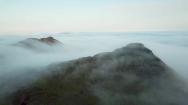 Aerial view of an amazing mist Faroese nature, foggy green hills and beautiful rocky cliffs and mountains. Flying above the clouds. High quality 4k footage
