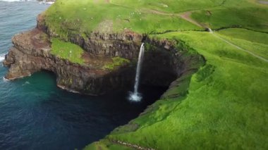Aerial view of Mulafossur waterfall, Faroe Islands. Small village Gasadalur with a Hvannadalur valley. Sunny day in summer. High quality 4k footage.