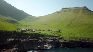Aerial view of Kalsoy island, Faroe Islands. Amazing Faroese nature, green hills and beautiful rocky cliffs and mountains. Kallur lighthouse. Sunny day in summer. Trollanes village. 4k footage